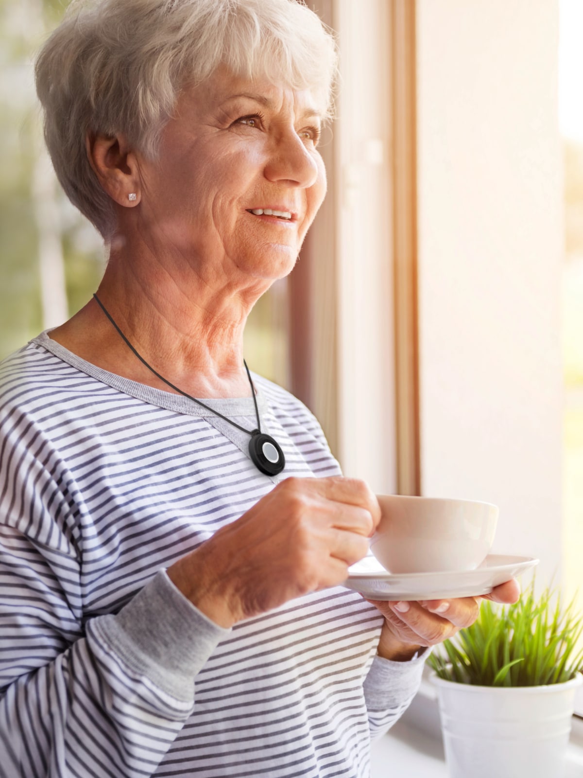 Woman drinking tea while wearing Medical Alert help button