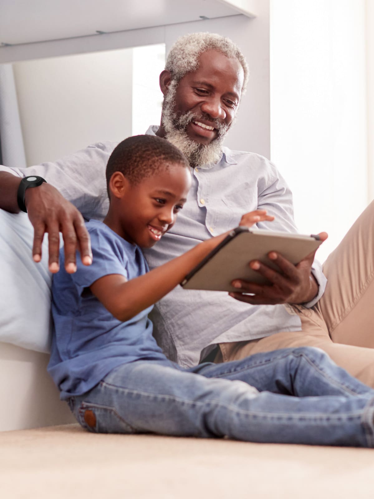 Grandfather wearing Medical Alert help button sits on floor with grandson