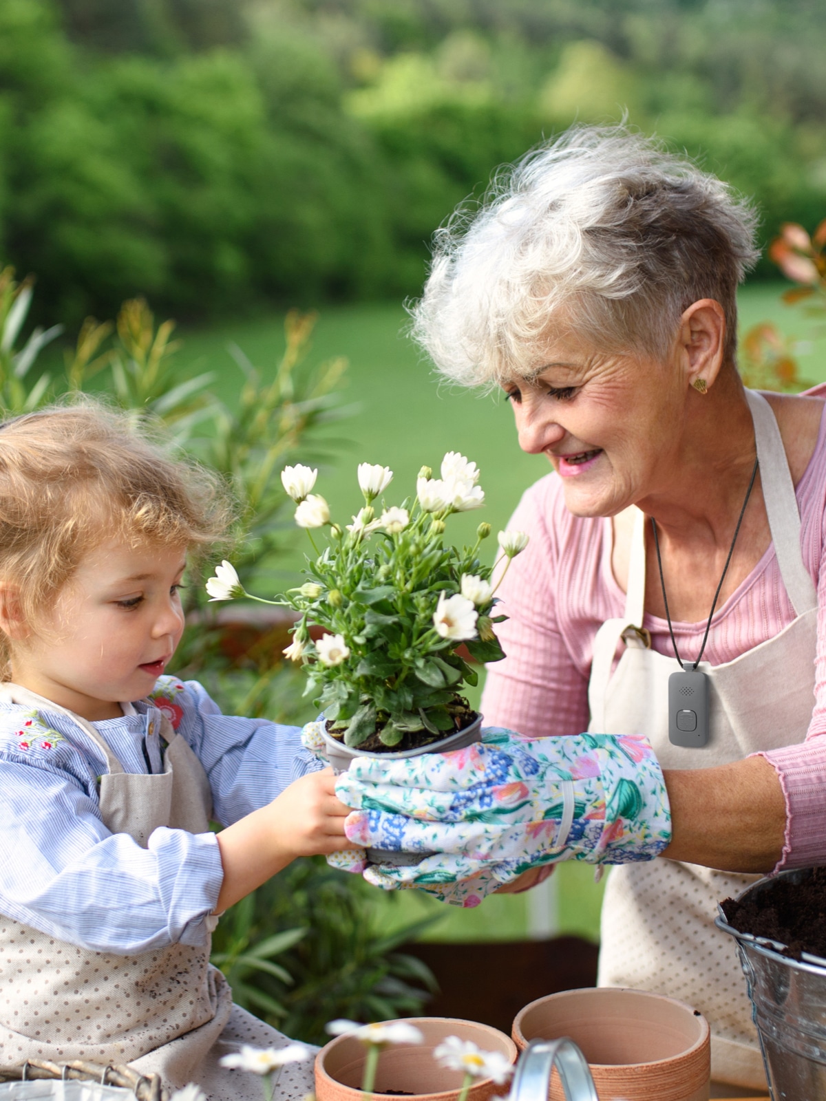 Woman wearing Medical Alert Mobile System while gardening with her granddaughter