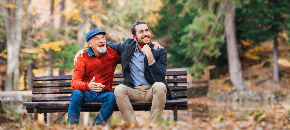 Father Son Sitting On Bench In Autumn