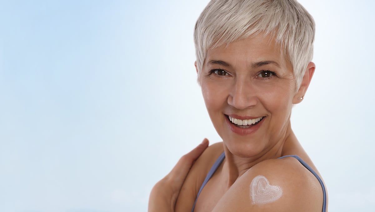 Happy Smiling Mature Woman Applying Moisturizing Cream