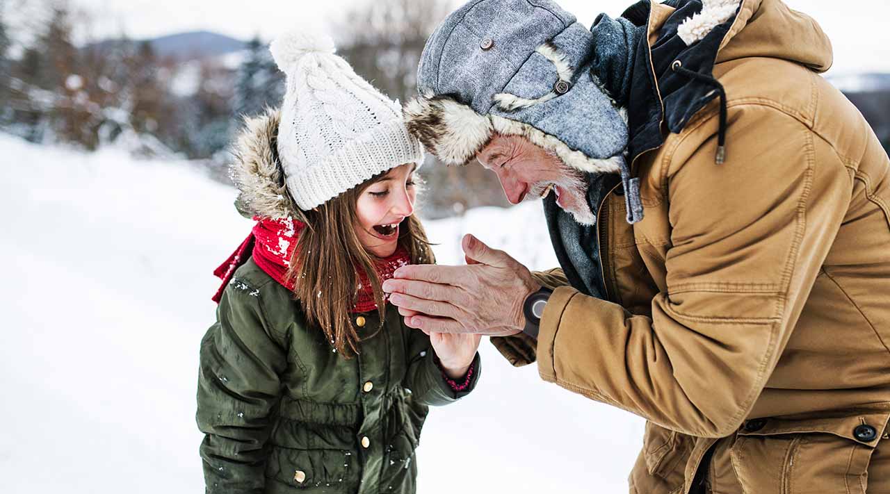 Man Wearing Medical Alert System Playing in Snow with Granddaughter